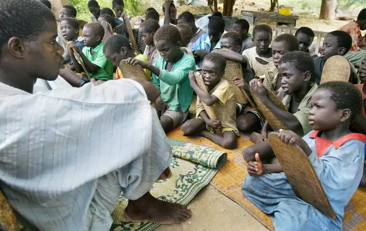 Talibés assis sur des nattes avec leurs tablettes coraniques en bois